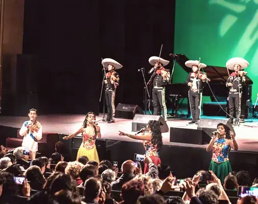 Mariachi y voces en un teatro lleno, en otro evento de Julieta.